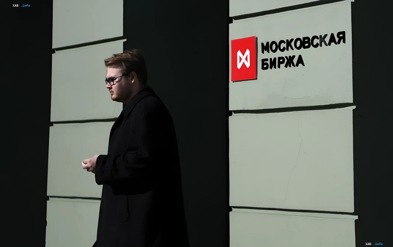 Человек проходит мимо здания Московской биржи на фоне новостей об обвале рынка из-за новых санкций США
