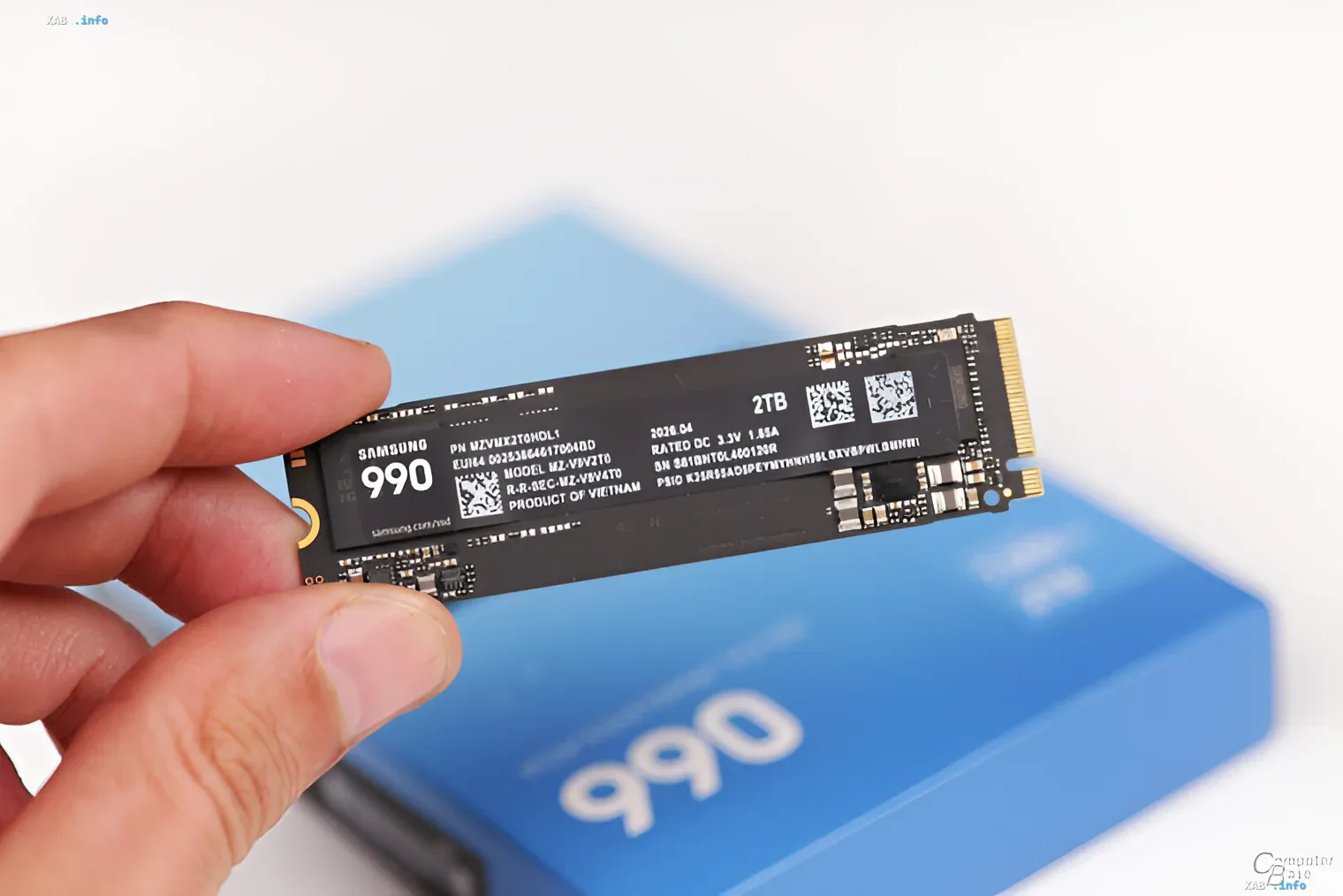 Samsung 990 SSD 2ТБ в руке на фоне синей упаковки, демонстрирующий новый продукт с разочаровывающим стартом