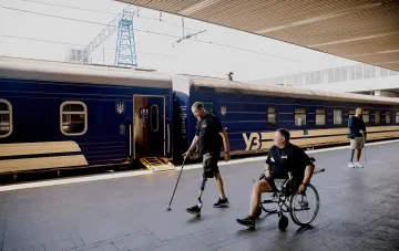 People with disabilities at a train station platform next to a Ukrainian Railways train, illustrating travel benefits