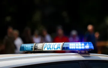 Сирена польской полиции с надписью POLICJA на фоне размытой толпы — символ правоохранительной реакции на инцидент с дроном над президентом