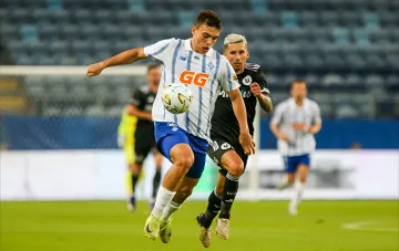 Kyiv Dynamo player in white jersey with GG logo battles for the ball against Universitatea Craiova opponent in decisive Europa League qualifier match