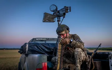 Ukrainischer Soldat mit Maschinengewehr auf Pickup-Truck bereitet sich auf Verteidigung vor während Russlands Massenangriff