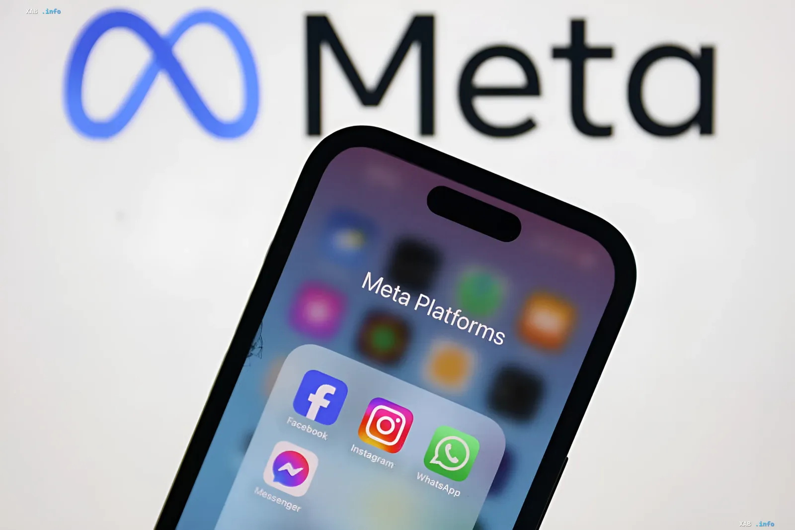 Смартфон с папкой Meta Platforms (Facebook, Instagram, WhatsApp, Messenger) на фоне логотипа Meta — иллюстрация к новости о системе экстренного оповещения родителей при угрозе суицида в чатах с AI