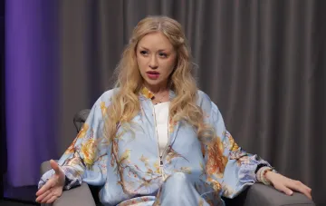 Natalia Valevskaya in a floral blue suit during an interview about motherhood and loss