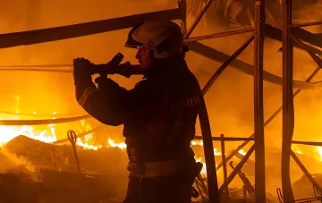 Пожежник гасить великий пожеж після нічного обстрілу Києва балістичними ракетами
