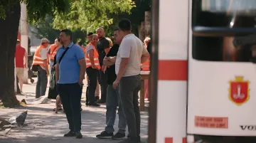 Люди та рятувальники на місці наслідків атаки в Одесі, поруч з аварійним автомобілем