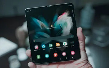 Samsung Galaxy Z Fold 8 в руке: раскрытый складной смартфон с титановым корпусом и ярким экраном, демонстрирующий интерфейс One UI и иконки приложений