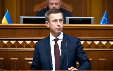 Sergey Koretsky bei einer Sitzung der ukrainischen Regierung mit Flaggen der Ukraine und der EU im Hintergrund