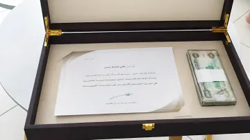Открытая подарочная коробка с письмом от Шейха Мухаммеда ибн Рашида Аль Мактума и денежной премией для лучшего выпускника школы ОАЭ