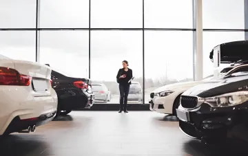 Frau in einem Autohaus betrachtet teure BMW-Autos, was das Thema der Luxussteuer in der Ukraine 2026 illustriert