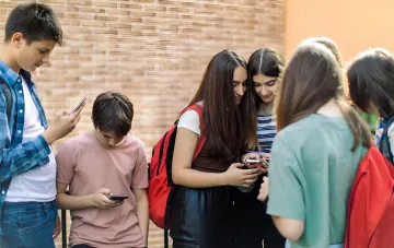 Группа украинских школьников общается, используя смартфоны, иллюстрируя переход к цифровым учебникам в 2026 году.