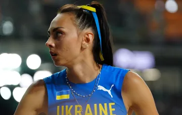 Украинская легкоатлетка Ирина Геращенко в синей форме с флагом Украины и надписью UKRAINE, на фоне стадиона — выбыла из Бриллиантовой лиги из-за визовых проблем