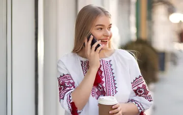 Молода жінка в вишиванці розмовляє по телефону, символізуючи повсякденне використання мови на тлі посилення норм в Україні