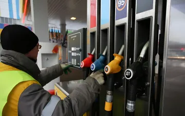 Оператор АЗС заправляє автомобіль дизельним паливом, ілюструючи дефіцит та необхідність імпорту палива в Росії.