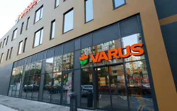 Fassade des Varus-Geschäfts mit orangefarbenem Logo und Blume, die die Expansion des Netzwerks und die Übernahme von 'Kolo' in der Ukraine symbolisiert