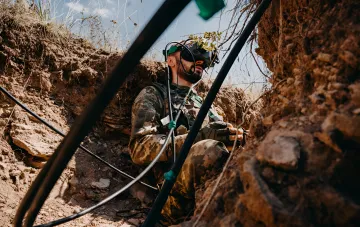 Украинский военнослужащий в окопе с VR-очками, символизирующий современные методы ведения войны и атаки на логистику