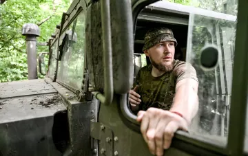 Украинский военный в камуфляже смотрит из окна военной машины в лесу — иллюстрация к новости о новых выплатах с 1 июня 2026 года