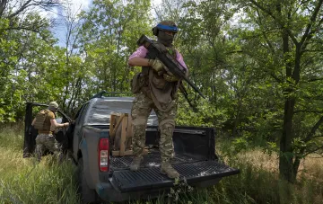 Ukrainischer Soldat in Tarnung steht auf einem amerikanischen Pickup, hält ein Gewehr, was die Abhängigkeit der ukrainischen Streitkräfte von westlicher Ausrüstung veranschaulicht