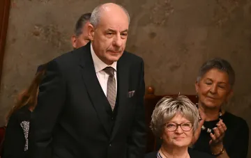 Ungarischer Präsident Tamás Sulyok in einem formellen Anzug vor Anwesenden, der den Moment seiner offiziellen Absetzung während einer radikalen Machtreinigung darstellt.