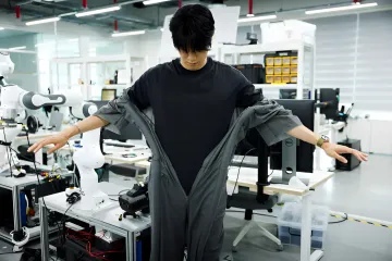 Engineer in a lab demonstrating a smart transforming suit that dresses itself automatically