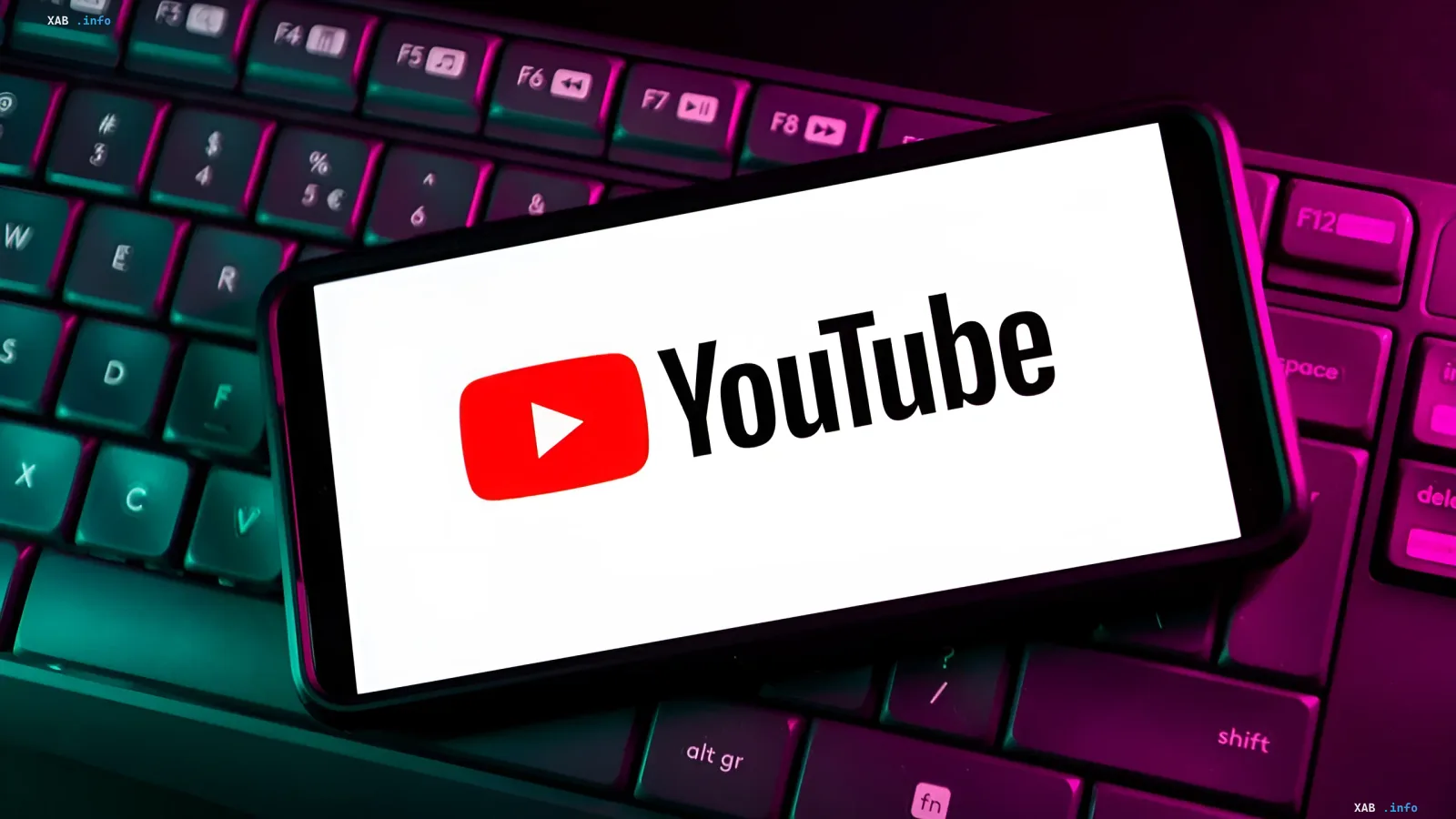 Смартфон с логотипом YouTube на экране, лежащий на клавиатуре с неоновой подсветкой, иллюстрирующий тему судебного разбирательства по поводу рекламы в YouTube Premium.
