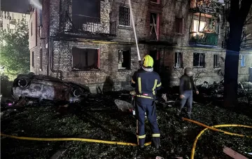 Aftermath of missile strike on Kyiv: firefighters extinguish burning building and burnt car at night