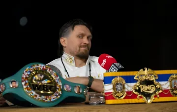 Александр Усик с поясами чемпиона мира на пресс-конференции, обсуждающий свои предпочтения в финале ЧМ-2026