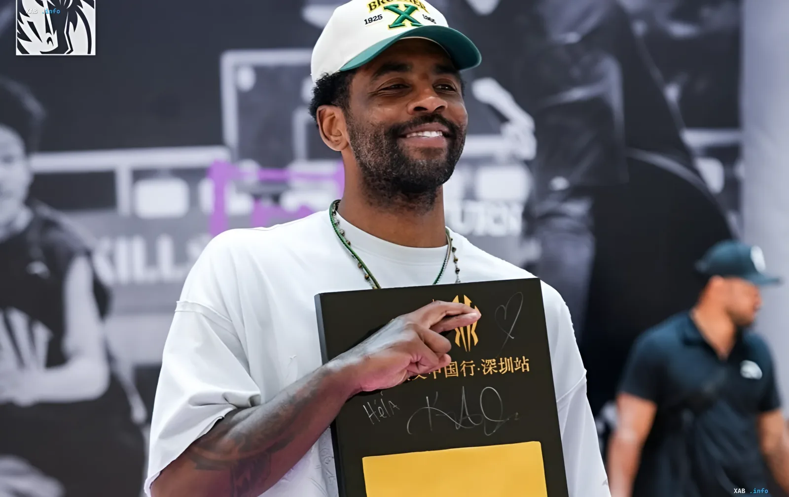 Kyrie Irving smiling while holding a gift box at an event in China, reinforcing his status as a key player of 'Dallas' who is not for sale
