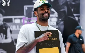 Kyrie Irving smiling while holding a gift box at an event in China, reinforcing his status as a key player of 'Dallas' who is not for sale
