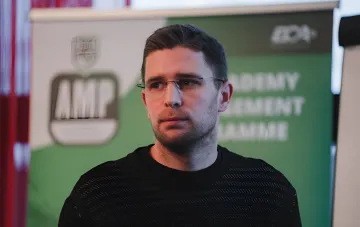 Артем Кравец в очках на фоне баннера с логотипом AMP, обсуждает шансы Испании и Аргентины в финале ЧМ-2026