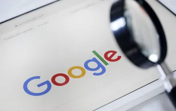 Логотип Google под увеличительным стеклом на экране ноутбука — символ технологических инвестиций США и Google в экономику Украины