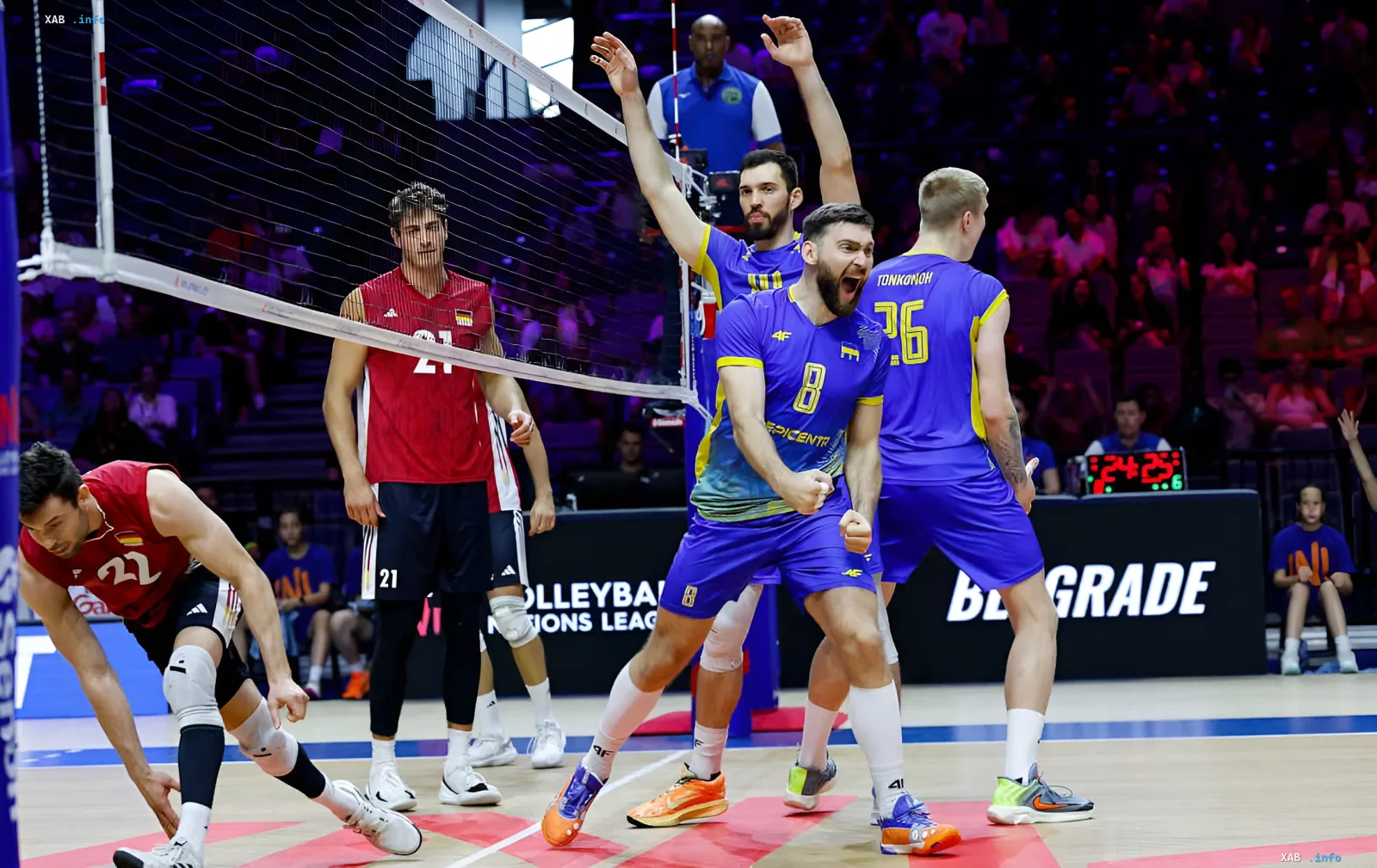 Ukrainische Volleyball-Nationalmannschaft in blauen Trikots feiert ihren historischen Sieg und den erstmaligen Einzug ins Playoff der Volleyball Nations League, im Hintergrund deutsche Gegner in Rot