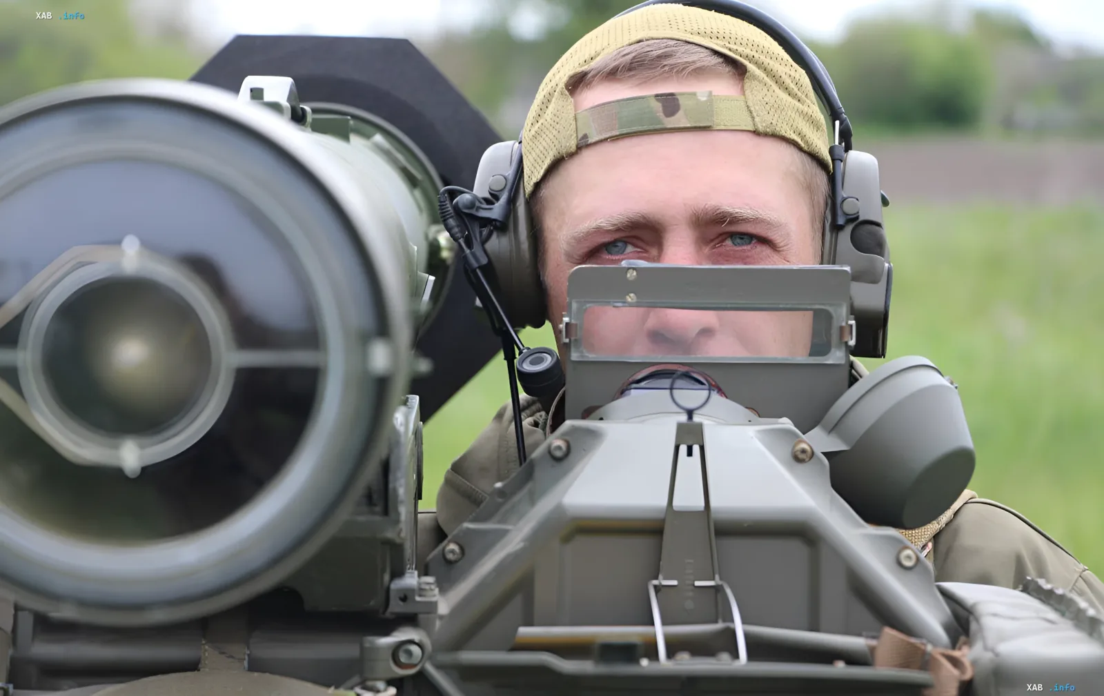 Ukrainischer Soldat mit Schutzhörern und Mütze zielt durch das Visier einer Flugabwehranlage während eines nächtlichen Luftangriffs