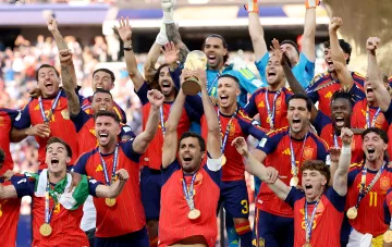 Spain national team celebrates victory at the World Cup, lifting the World Cup trophy, while players in red and blue jerseys joyfully shout and raise their hands