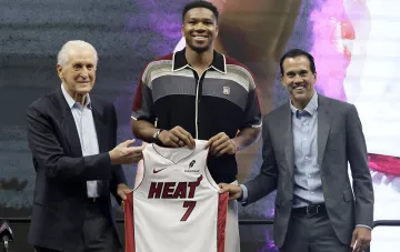 Giannis Antetokounmpo with Jerry Reinsdorf and Erik Spoelstra holding Miami Heat jersey number 7, symbolizing his move from Milwaukee