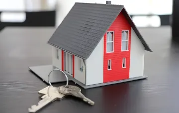 Hausmodell mit Schlüsseln auf Tisch — Symbol für steigende Mietpreise im Umland von Kiew, die nun mit denen der Hauptstadt gleichziehen