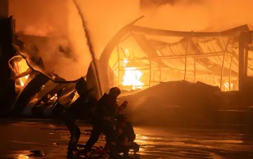 Пожежники гасять палаючу будівлю в Сумах після ворожої атаки, на фото видно зруйновану конструкцію та вогняний фон