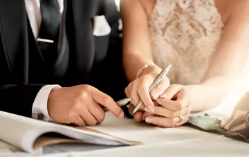 Підписання шлюбного контракту або фіктивного шлюбу в Україні: руки нареченого та нареченої з перами над документами
