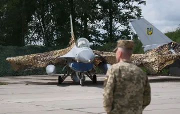 Ukrainian F-16 fighter jet with camouflage netting on an airfield, symbolizing the first aerial victory over a Russian aircraft