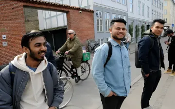 Gruppe indischer Studenten spaziert auf einer europäischen Straße und wählt einen neuen Weg statt Amerika