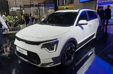 Белый электромобиль Kia e-Niro на выставке, демонстрирующий долговечность батареи