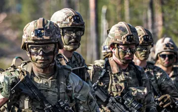 Військовики НАТО в камуфляжі з озброєнням на фоні лісу, що символізують готовність до ескалації та посилення ППО
