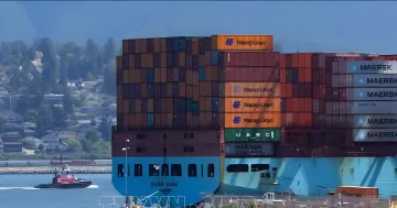 Вантажний контейнеровоз з контейнерами Maersk та Hapag-Lloyd у порту, що ілюструє наслідки торгової війни США та Канади