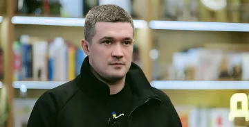 Екс-міністр Олексій Федоров у чорній куртці з українським прапором на фоні книжкових полиць, обговорюючи свої плани на президентський пост