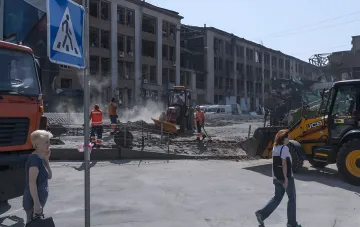 Zerstörtes Gebäude und Baumaschinen im Hintergrund von Wiederherstellungsarbeiten nach Beschuss in der Ukraine