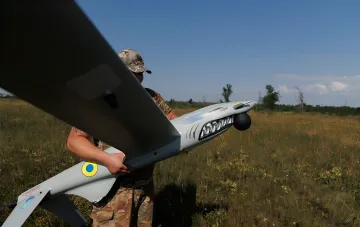 Український бійці в камуфляжі тримає розвідувальний дрон з українським опізнавальним знаком на фоні поля — ілюстрація до новини про нейтралізацію РЛС «Буссоль» та пунктів керування дронами ЗСУ