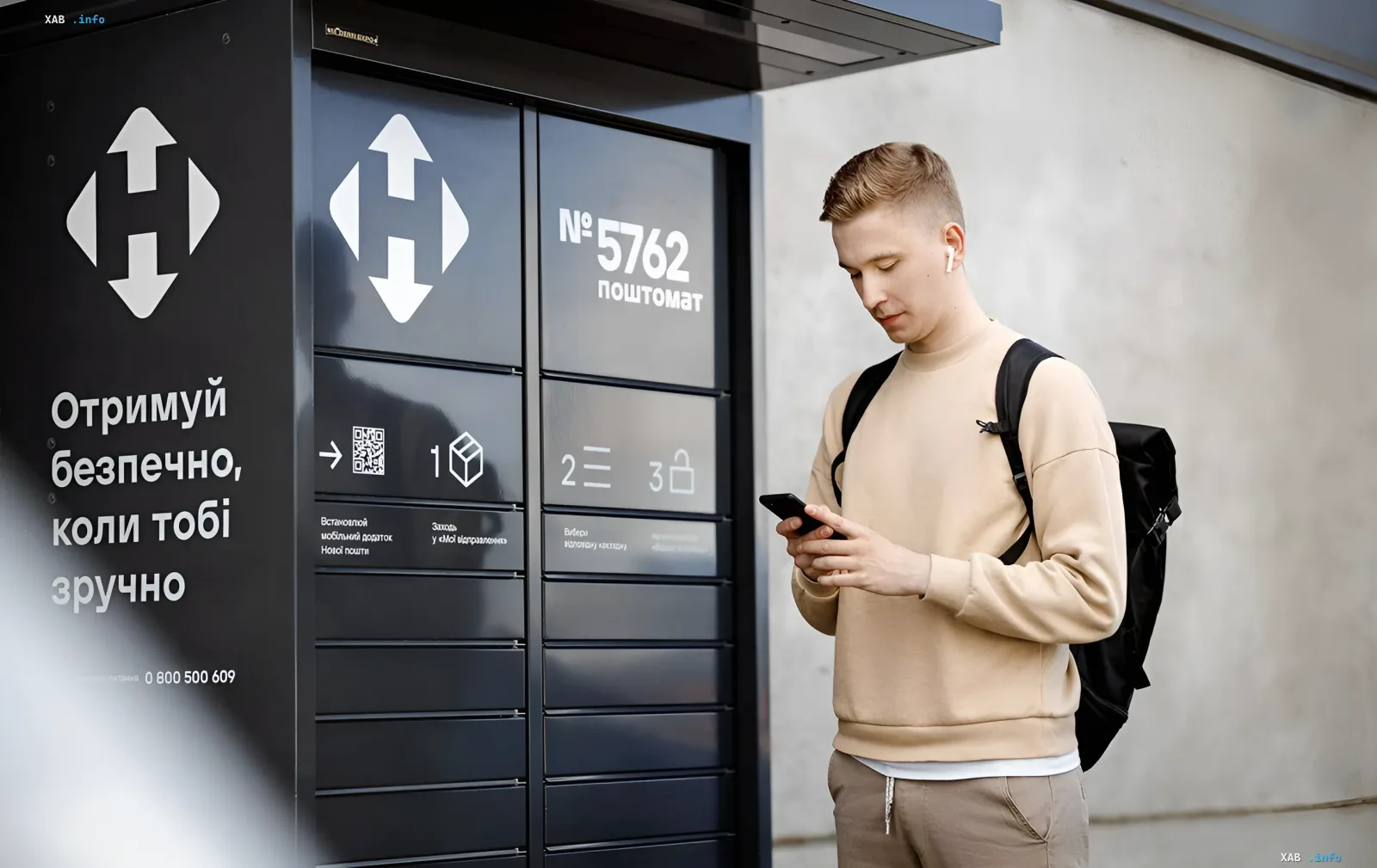 Молодой человек у почтомата Новой почты проверяет сообщение на смартфоне — иллюстрация к статье о фишинге под видом налоговой проверки