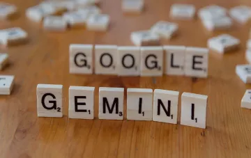 Деревянные фишки с надписями Google и Gemini на деревянном столе, символизирующие обновление линейки ИИ-моделей Google Gemini