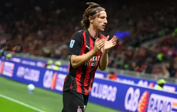 Luka Modric in AC Milan's red-and-black kit applauding on the pitch, set to extend his contract at age 41