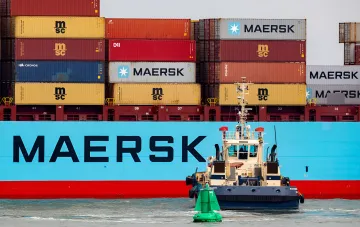 Крупный контейнеровоз Maersk с буксиром на фоне, символизирующий остановку сервиса через Черноморский рыбный порт из-за обострения ситуации в регионе.